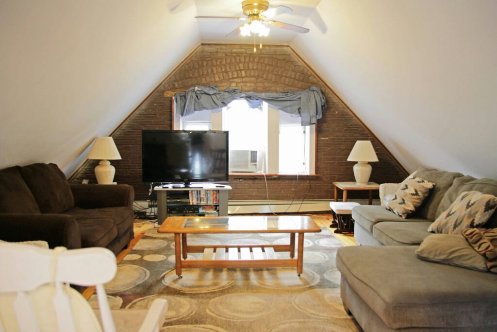 Cozy attic living room with sofas, coffee table and TV under sloped ceiling